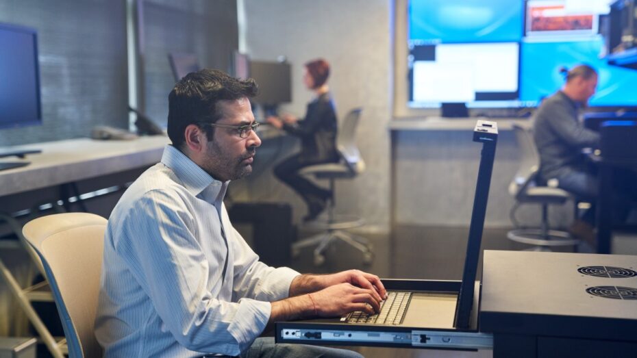 Man in a collared shirt working on a server station inside a secure room.