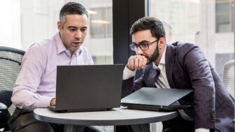 a man sitting at a table using a laptop computer