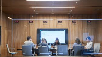 Looking into a conference room or board room meeting including people sitting around table in a room with international time clocks.