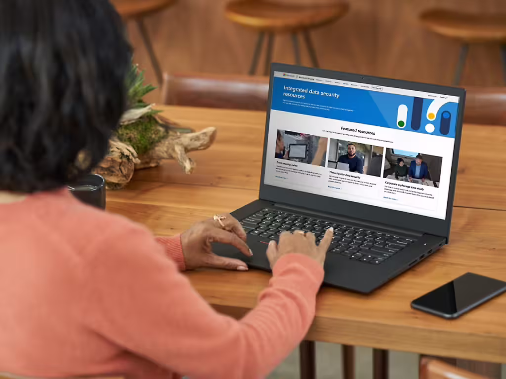 Person typing on laptop with Microsoft integrated data security resources screen.