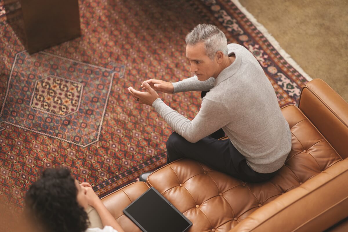 Two employees chat while sitting on a coach in a gathering space in a Microsoft building.